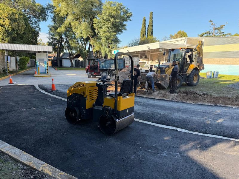 Rodillo compactador y retroexcavadora CAT trabajando en obra de asfaltado