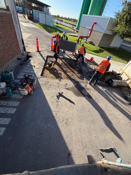 Bacheo con concreto asfáltico fresco en planta industrial con cuadrilla de trabajo