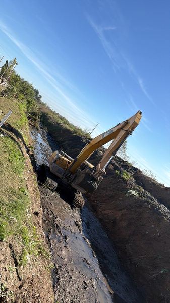 Excavadora CAT operando en zanja de arroyo para obra hidráulica